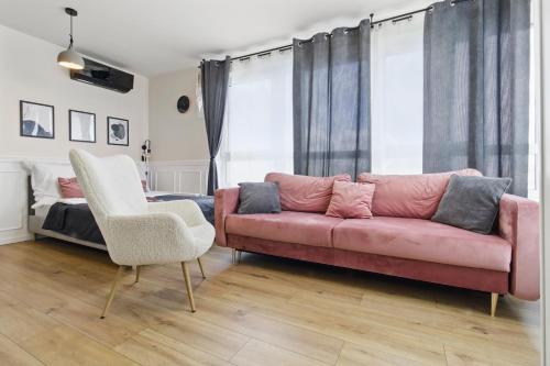 a living room with a pink couch and a bed at Stylowy apartament z balkonem i panoramą miasta in Siedlce