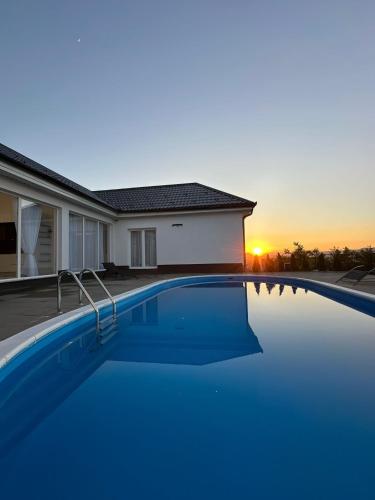 a swimming pool in front of a house with the sunset at Amal Residence in Sarajevo