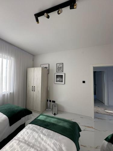 a white bedroom with a bed and a cabinet at Amal Residence in Sarajevo