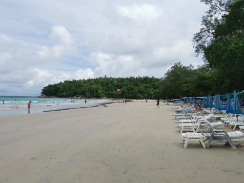 a beach with white chairs and people on the beach at 8 Floor - Mountain view Studio room at TBHR near Kata beach in Kata Beach