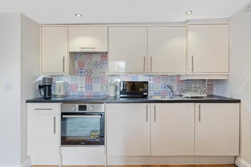 a white kitchen with white cabinets and appliances at Entire City Centre one bedroom Apartment- Self check in FREE PARKING in Chichester