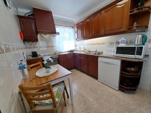 a kitchen with wooden cabinets and a table and a microwave at Quinta Rural em Coruche com piscina privativa in Coruche