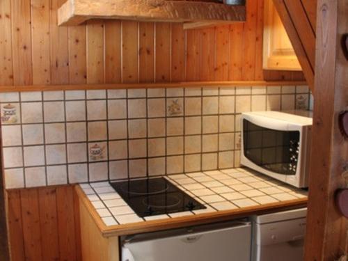 une cuisine avec une cuisinière et un micro-ondes dans l'établissement Chalet 3* cosy aux Gets, Wi-Fi, 450m télécabine, 2 chambres, parking privé, balcon sud/est - FR-1-671-40, aux Gets