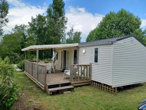 une petite maison blanche avec une terrasse et un belvédère dans l'établissement Mobilhomes Cozy 2 ou 3 chambres en bordure d'étang Camping 3 étoiles, à Ivry-la-Bataille
