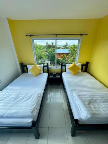 two beds in a room with a window at KK Hotel in Pakse