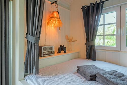 a bedroom with a bed and a window and a radio at Nature lovers Amsterdam Zaandam in Wijdewormer