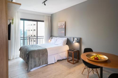 a bedroom with a bed and a table with a bowl of fruit at Paraíso Paulista Flats by Feel Sampa in Sao Paulo