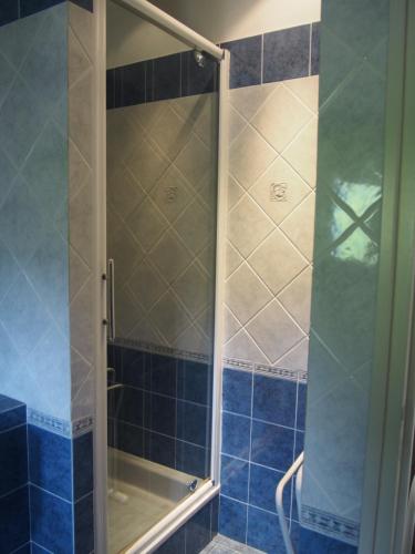 La salle de bains est pourvue d'une douche et de carrelage bleu. dans l'établissement LA MAISON BLEUE Piscine Grand Jardin - 4 CHh- 3 Sdb, à La Celle-sous-Gouzon