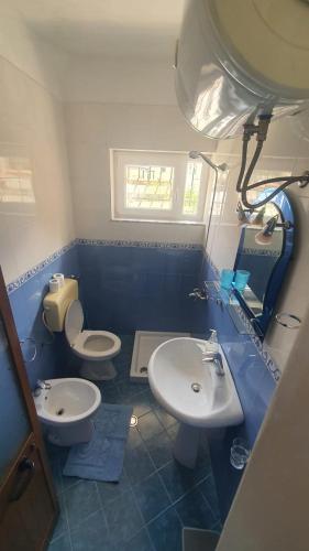 a blue and white bathroom with two sinks and a toilet at The Cozy Home in Krujë