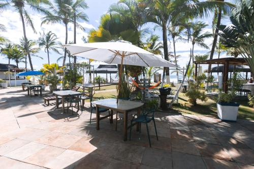a patio with tables and chairs and an umbrella at Indaiá Eco Village in Ilhéus