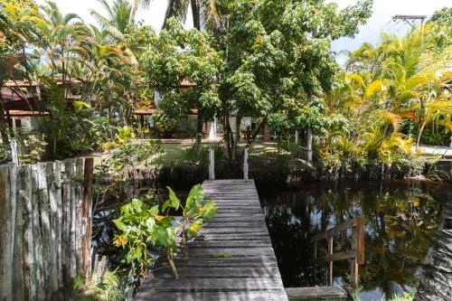 a wooden bridge over a body of water with trees at Indaiá Eco Village in Ilhéus