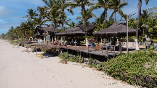 a beach with a bunch of chairs and umbrellas at Indaiá Eco Village in Ilhéus