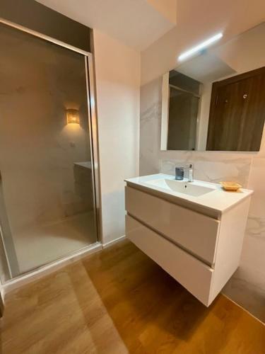 une salle de bain avec un lavabo blanc et une douche dans l'établissement Luxueux T4 de 100m2 avec roof top, piscine et plage, à Pianottoli-Caldarello