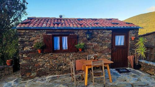 una pequeña casa de piedra con una mesa delante en Refúgio do Casal, en Lousã