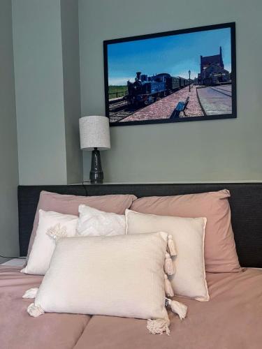 a television hanging above a bed with pillows at Huisje 10D in Medemblik