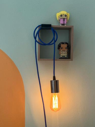 a light hanging from a wall with a light on it at Blue Bergamote - Pop Culture Suite in Ermoupoli