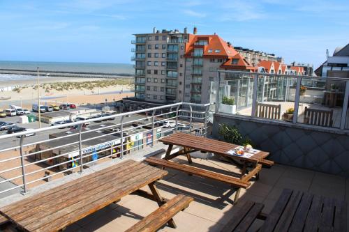two benches sitting on top of a balcony overlooking a beach at Hotel Uilenspiegel in Nieuwpoort