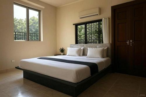 a bedroom with a large bed and two windows at Hotel Ayushman Grand in Jabalpur