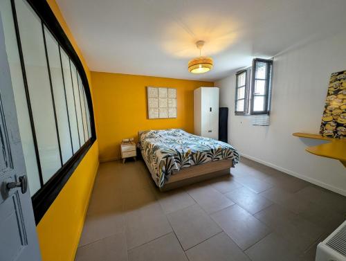 - une chambre avec un lit et un mur jaune dans l'établissement maison de campagne proche mer 12 pers, à Lussant