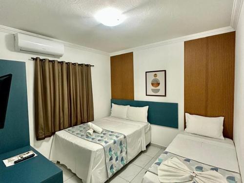 a hotel room with two beds and a window at Pousada Caribe Brasileiro in Maragogi