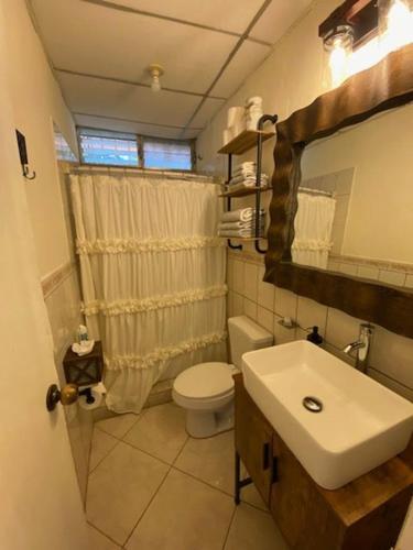 a bathroom with a white toilet and a sink at Nica Mango Tree Casa in Managua