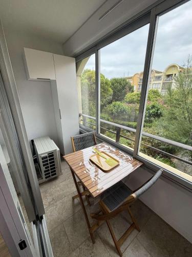 une table et des chaises dans une pièce avec une fenêtre dans l'établissement Superbe Appartement T2 climatisé, à Gruissan