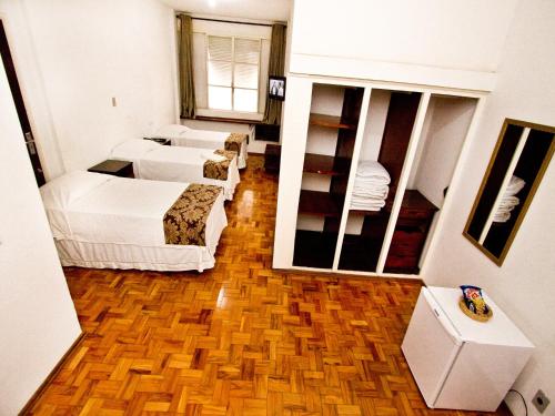 een kamer met 4 bedden en een grote spiegel bij Turrance White Hotel in Campinas