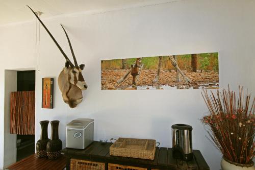 a room with a table and a picture of a deer on the wall at Normann Safari Bush Lodge in Phalaborwa
