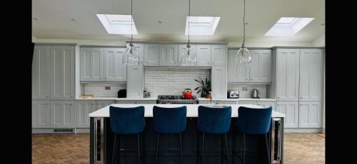 a kitchen with white cabinets and a island with blue chairs at HAYFIELD COTTAGE spacious detached luxury home in Copmanthorpe