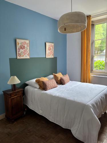 une chambre avec un grand lit avec un mur bleu dans l'établissement Maison Mère, à Arnac-Pompadour