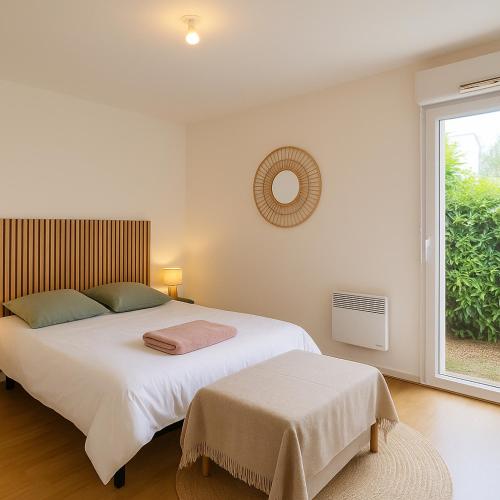 une chambre avec un grand lit blanc et une fenêtre dans l'établissement T3 cosy avec jardin et parking, calme et nature, à Bouchemaine