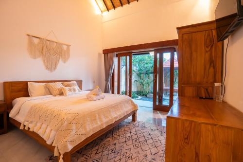 a bedroom with a bed and a large glass door at Nukulla House in Tumbak Bayuh