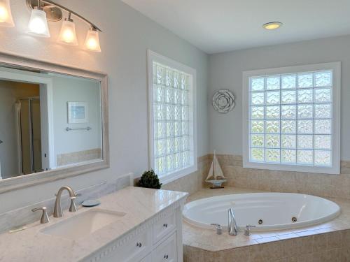 une salle de bain avec une baignoire et un grand miroir dans l'établissement SNH263 Gone Coastal, à Nags Head