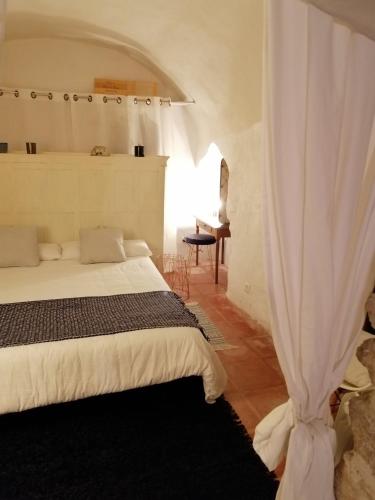 a bedroom with a white bed and a window at Le Castel in Châteauneuf-du-Pape