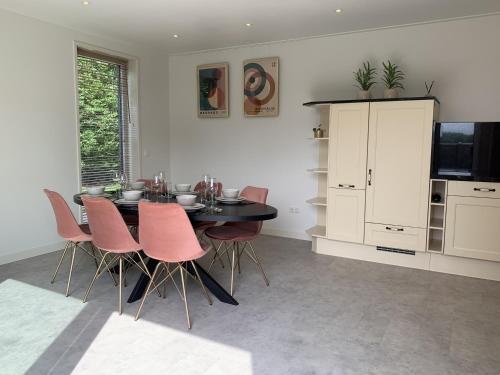 a dining room with a table and pink chairs at Huis van alle winden in Ovezande