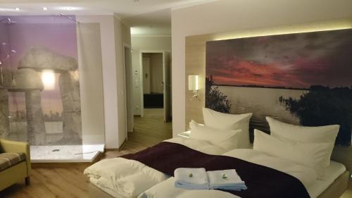 アンガーミュンデにあるFlair Hotel Weissの大きなベッド付きのベッドルーム1室、壁に絵画が飾られています。