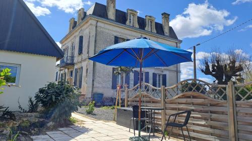 a blue umbrella sitting in front of a house at La Maison de Maître Chagnon Aumagne in Aumagne