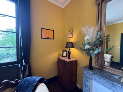 a room with yellow walls and a table with a lamp at La Maison de Maître Chagnon Aumagne in Aumagne
