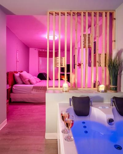 a pink room with a bed and a table with wine glasses at Le Lovely Narbonnais - Balneo & Sauna in Narbonne