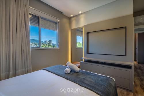 a bedroom with a flat screen tv and a bed at Estadia sofisticada a 200m da Praia Brava - EHI in Praia Brava