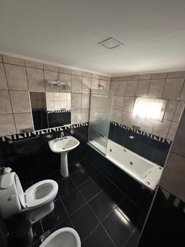 a bathroom with a toilet and a sink and a tub at Hotel Silver Golf in Sierra de la Ventana