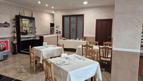 a restaurant with white tables and chairs and a kitchen at Hotel La Vecchia Quercia in Cerreto Sannita