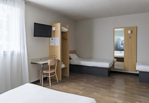 a room with two beds and a table and a mirror at B&B HOTEL Montargis-Amilly in Amilly