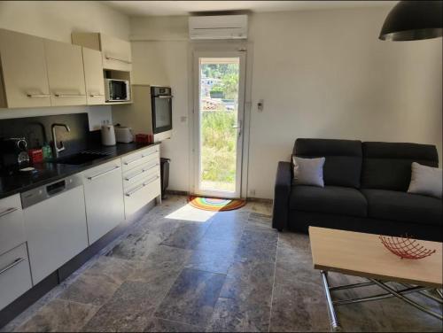 a living room with a black couch and a kitchen at Maison d'hôtes à Allauch in Allauch