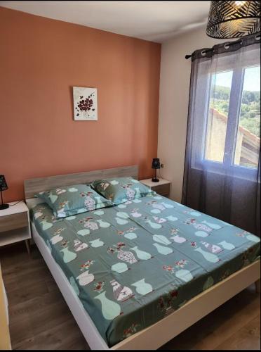 a bedroom with a bed with a green comforter and a window at Maison d'hôtes à Allauch in Allauch