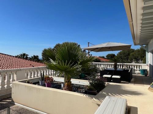 - une terrasse avec un banc, une table et un parasol dans l'établissement Appartement vue mer à la semaine uniquement, à Saint-Aygulf