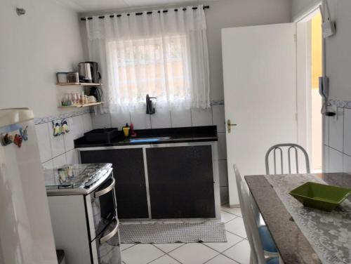 uma cozinha com pia e fogão forno superior em CASA a 550 METROS DA SAÍDA DOS PASSEIOS DE BARCO NA PRAIA DOS ANJOS 1 VAGA DE GARAGEM em Arraial do Cabo