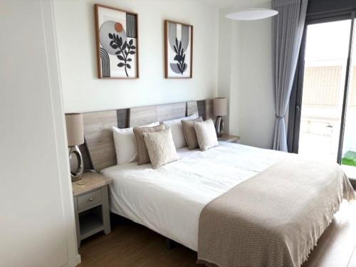 a bedroom with a large white bed and a window at Denia Apartment Rental - Vivir La Vida in Denia