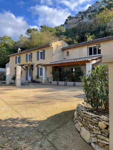 un grand bâtiment avec un mur en pierre devant lui dans l'établissement Fontaine de bonheur, à Fontaine-de-Vaucluse