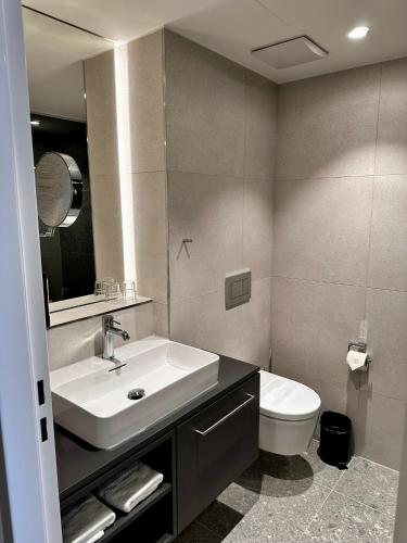 a bathroom with a white sink and a toilet at Stadthotel Münster in Münster